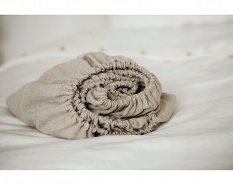 May include: A rolled up beige linen fitted sheet. The sheet is made of a soft, natural fabric and is perfect for a comfortable night's sleep.