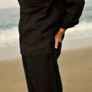 Pu&ograve; includere: Un completo in lino nero composto da una camicia e pantaloni. La camicia ha un colletto abbottonato e una tasca sul petto sinistro. I pantaloni hanno una gamba dritta.