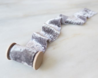 May include: A spool of silver gray velvet ribbon with a wooden spool.