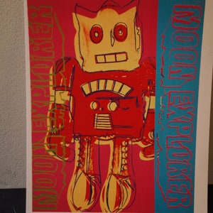 Könnte beinhalten: Eine Illustration eines roten, gelben und blauen Roboters mit dem Text "Moon Explorer" in goldenen Buchstaben auf der linken Seite und "Moon Explorer" in blauen Buchstaben auf der rechten Seite.