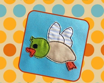 May include: A blue felt applique of a duck with green and white wings on a blue background with a polka dot border. The text "Duck Raggy Applique" is at the top of the image and the text "Backyard Stitch'n" is at the bottom of the image.