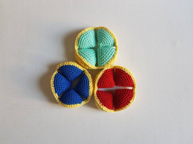 May include: Three crocheted balls with yellow trim. The balls are divided into four sections each. The sections are blue, red, and light blue.