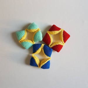 May include: Three crocheted star-shaped toys in blue, red, and green with yellow accents. The toys are made of soft yarn and are perfect for a baby or toddler.