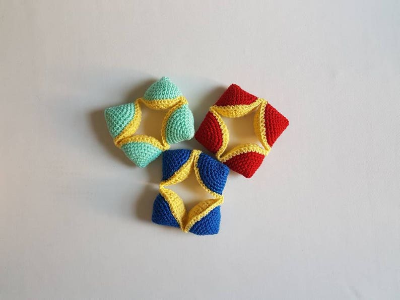 May include: Three crocheted star-shaped toys in blue, red, and green with yellow accents. The toys are made of soft yarn and are perfect for a baby or toddler.