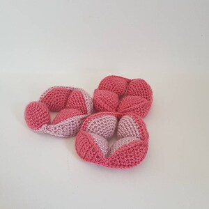May include: Three pink and light pink crocheted balls, each with a unique shape and design. The balls are made of soft yarn and are perfect for sensory play or as a decorative element.