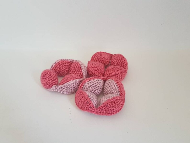 May include: Three pink and light pink crocheted balls, each with a unique shape and design. The balls are made of soft yarn and are perfect for sensory play or as a decorative element.