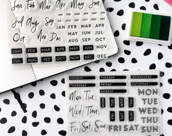 May include: Clear acrylic stamp set with black lettering for months of the year, days of the week, and the words "Mon Tue Wed Thu Fri Sat Sun".