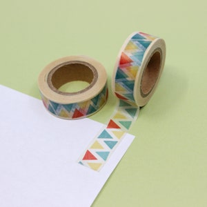 May include: Two rolls of washi tape with a geometric pattern of yellow, red, blue, and green triangles. One roll is unwinding and the tape is laying on a white surface.