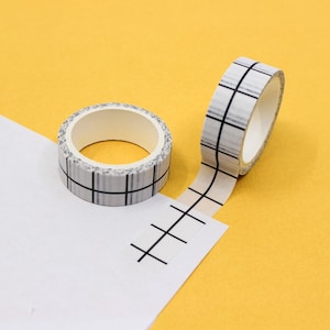 May include: Two rolls of white and black patterned washi tape. One roll is partially unrolled, showing the tape's design.