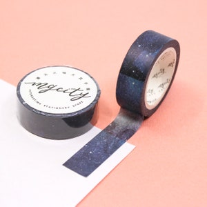 Puede incluir: Un rollo de cinta washi negra y azul con un estampado de galaxia. La cinta est&aacute; etiquetada "mycity interesting stationery store" en texto blanco.