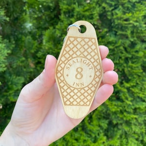 May include: Wooden key chain shaped like a motel key with the text "Sealight Inn" and the number "8" in a circle. The key chain has a diamond pattern.