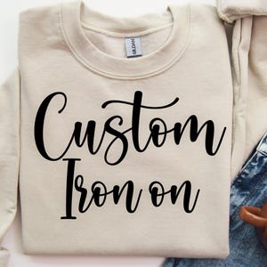 May include: A handmade wooden sign with the text "Welcome" in a playful font. The sign is painted white with a distressed finish, and features a decorative floral design in shades of pink and green. It measures approximately 12 inches wide.