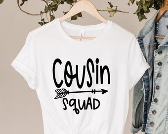 May include: White t-shirt with black text that reads "Cousin Squad" and a black arrow pointing to the right.