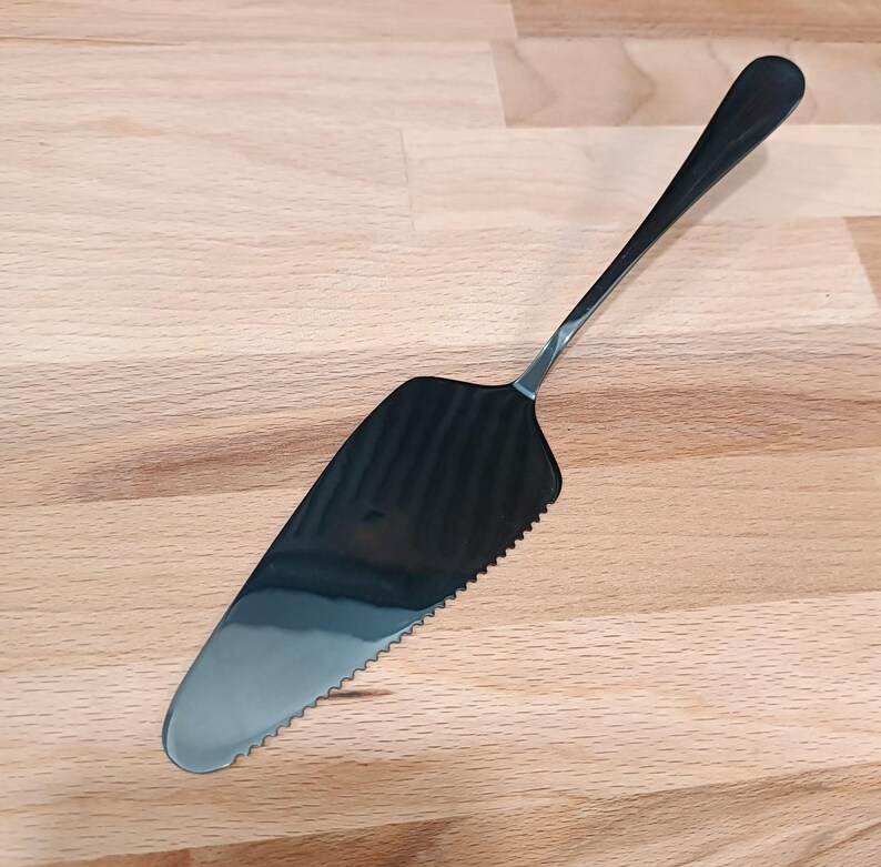 a plastic spatula with a black handle on a wooden surface