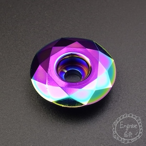 Könnte beinhalten: Eine facettierte Perle in Regenbogenfarben mit einem Loch in der Mitte. Die Perle ist rund und hat eine flache Ober- und Unterseite.