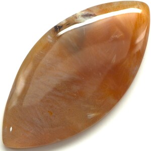 May include: A polished, elongated gemstone with a warm, earthy color palette. The stone features a blend of orange, brown, and cream hues, with a glossy, reflective surface. The shape is reminiscent of a leaf or an eye, perfect for jewelry.