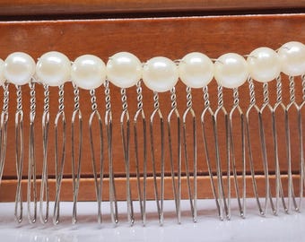 May include: A decorative hair comb featuring a row of large, creamy-white faux pearls. The pearls are attached to a silver-toned metal base with multiple teeth. The comb is designed for securing hair and adding a touch of elegance.