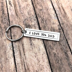 May include: Silver keyring with a rectangular tag that reads "I LOVE YOU DAD" in handwritten font.