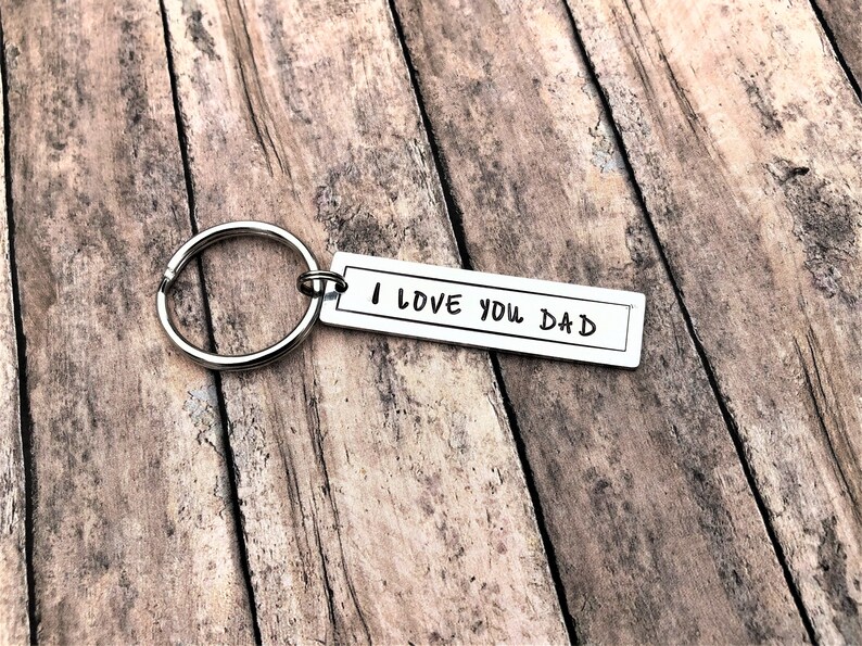 May include: Silver keyring with a rectangular tag that reads "I LOVE YOU DAD" in handwritten font.