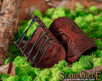 May include: Two brown leather arm bands with intricate Celtic knot designs. One band has a black leather lacing system.