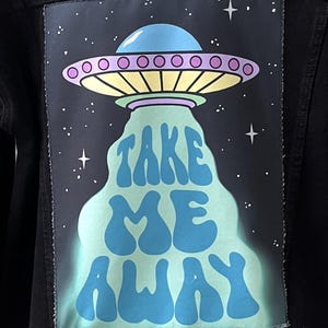 May include: A black denim jacket with a colorful patch on the back. The patch features a cartoon UFO with the text "TAKE ME AWAY" in a retro font.