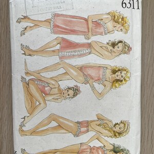 Könnte beinhalten: Ein New Look 6311 Schnittmusterumschlag mit Illustrationen von fünf verschiedenen Lingerie-Stilen in Rosatönen mit weißer Spitzenborte. Die Entwürfe umfassen verschiedene Längen von Unterkleidern, Camisoles und Shorts auf weißem Grund.