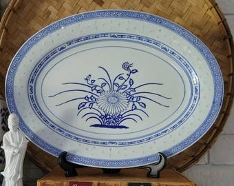 May include: A white oval serving platter with a blue and white floral design. The platter has a blue border with a repeating pattern of lines and dots.