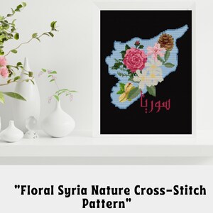 Puede incluir: Un patrón de punto de cruz digital que presenta un diseño floral con la forma de Siria. El patrón está en tonos de rosa, blanco, verde y azul. La palabra "Siria" está escrita en árabe en el centro del diseño. El patrón está disponible como una impresión digital PDF.
