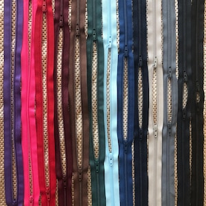 Könnte beinhalten: Eine Auswahl an Reißverschlussbändern in verschiedenen Farben, darunter Lila, Pink, Rot, Weinrot, Braun, Dunkelgrün, Hellblau, Dunkelblau, Beige, Grau und Schwarz.