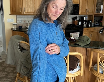 May include: A blue heathered long-sleeve pullover featuring a quarter-zip neckline and a vertical zipper detail running along the outer length of the sleeve. The garment is constructed from a textured knit fabric and includes a front pocket.
