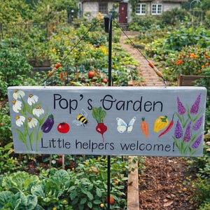 May include: A gray wooden sign that reads "Pop's Garden" with painted illustrations of vegetables, a bee, and a butterfly. The sign also says "Little helpers welcome!" and is displayed in a garden setting with a cottage in the background.