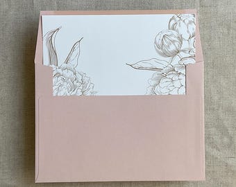 Può includere: Una busta rosa cipria con una carta con un'illustrazione floreale. La carta presenta un disegno a tratto dettagliato di peonie nei toni del marrone. La busta è di un rosa tenue, creando un'estetica elegante e delicata.