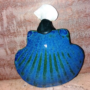 Op de afbeelding: Een blauwe en groene keramische schelp met een witte top. De schelp heeft een glanzende afwerking en is versierd met een textuurpatroon.