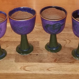 Puede incluir: Cuatro copas de cerámica de color morado y verde con bordes dorados. Las copas tienen un diseño único con un patrón de espiral.