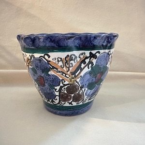 May include: A blue and white ceramic planter with a scalloped rim and a floral design. The flowers are painted in shades of blue, green, orange, and brown.