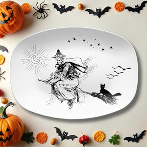 May include: White oval serving platter with a black and white illustration of a witch flying on a broomstick, with a black cat. The design includes stars, a crescent moon, and flying birds. Halloween themed.