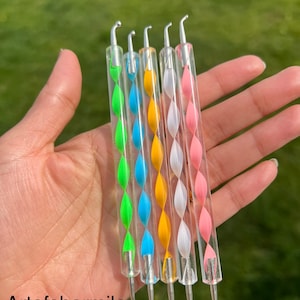 May include: Set of five nail art tools with clear handles and colorful swirl designs. The tools have a silver metal tip.