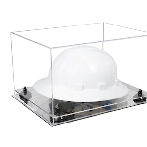 May include: A clear acrylic display case with a white hard hat inside. The case has a black base with four rubber feet.