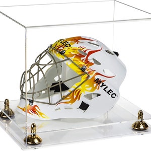 May include: A white hockey goalie mask with a yellow and orange flame design and the word "MYLEC" on the side, displayed in a clear acrylic display case with a gold base.