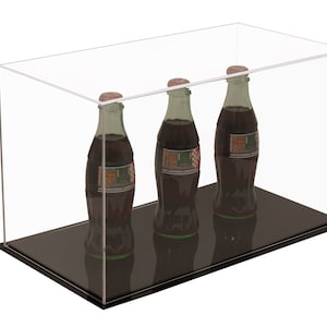 May include: A clear acrylic display case containing three glass bottles filled with a dark liquid. Each bottle features a label with a large orange letter T and the text 1998 NATIONAL CHAMPIONS. The case has a solid black rectangular base.