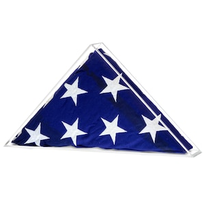 May include: A clear acrylic triangular display case with a folded American flag inside. The flag is blue with white stars.