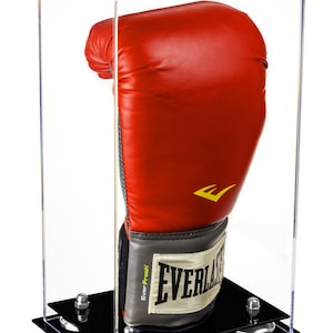 May include: A red Everlast boxing glove displayed in a clear acrylic case with a black base. The glove has a yellow logo and a gray and white wrist strap. The case is designed to protect and showcase the boxing glove.
