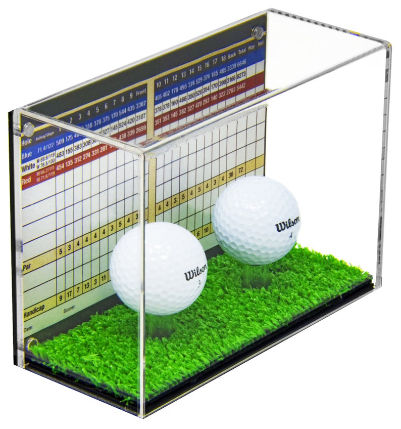 Op de afbeelding: Een transparante acryl display met twee witte golfballen op een groene kunstgrasbasis. De display heeft een scorekaart aan de zijkant met de tekst "Red 71 6/11/19 454 135 312 274 331 281".
