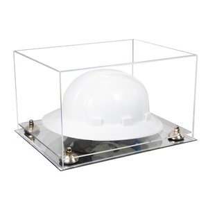 May include: A white hard hat displayed inside a clear acrylic case. The case has a mirrored base and is secured with four silver-colored fasteners. The hard hat is a standard construction helmet.