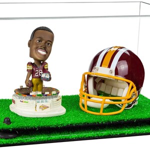 May include: A clear acrylic display case with a green artificial grass base. Inside the case is a burgundy and gold football helmet and a bobblehead of a football player wearing a burgundy and gold jersey with the number 28.