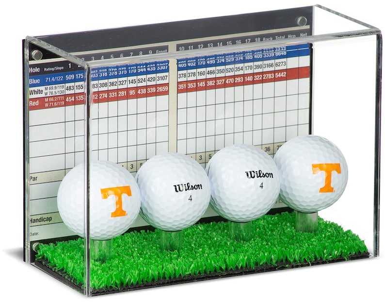 Op de afbeelding: Een transparante acryl displaykast met een groene grasbasis en vier golfballen. De golfballen zijn wit met oranje en zwarte logo's. De kast heeft een scorekaart aan de zijkant met de tekst "Total Men Net".