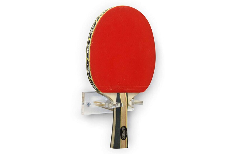 May include: A clear acrylic wall mount for storing a ping pong paddle. The paddle has a red rubber surface and a wooden handle with the word "APEX" printed on it.