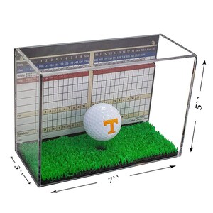 Op de afbeelding: Een transparante acryl display met een golfbal met het logo van de Tennessee Volunteers. De display is 17,8 cm breed, 7,6 cm diep en 12,7 cm hoog. De display bevat een groene kunstgrasbasis en een scorekaart.