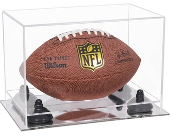 May include: A brown leather NFL football with white laces, featuring the text THE DUKE, Wilson, and COMMISSIONER, enclosed in a clear rectangular acrylic display case with four black support mounts on a reflective base for sports memorabilia.