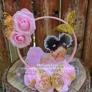 Pode incluir: Um topo de bolo circular rosa com duas rosas de espuma, tr&ecirc;s borboletas de filigrana met&aacute;lica dourada e um recorte central de um beb&eacute; com cabelo encaracolado escuro, tutu rosa e chupeta, com o texto MyCurlyLove www.etsy.com/shop/MyCurlyLove.